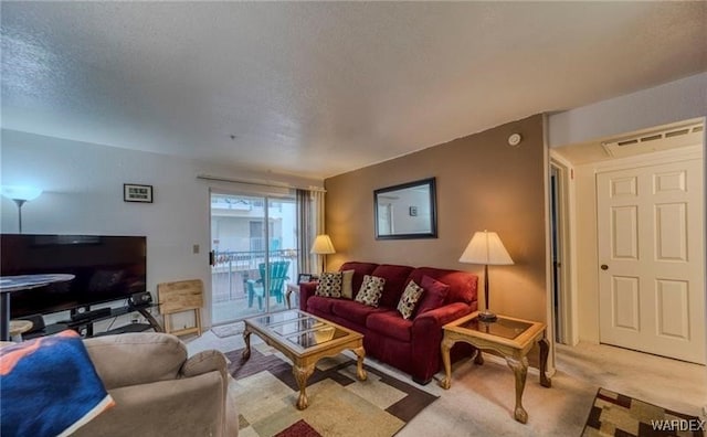 living area with visible vents, light colored carpet, and a textured ceiling