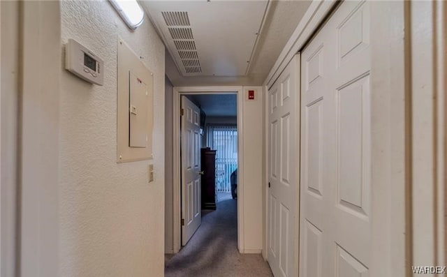 hallway featuring electric panel, dark colored carpet, and a textured wall