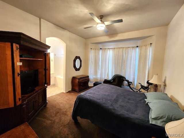 bedroom with arched walkways, ensuite bathroom, a ceiling fan, and light colored carpet