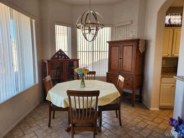 dining area featuring a notable chandelier, arched walkways, and baseboards