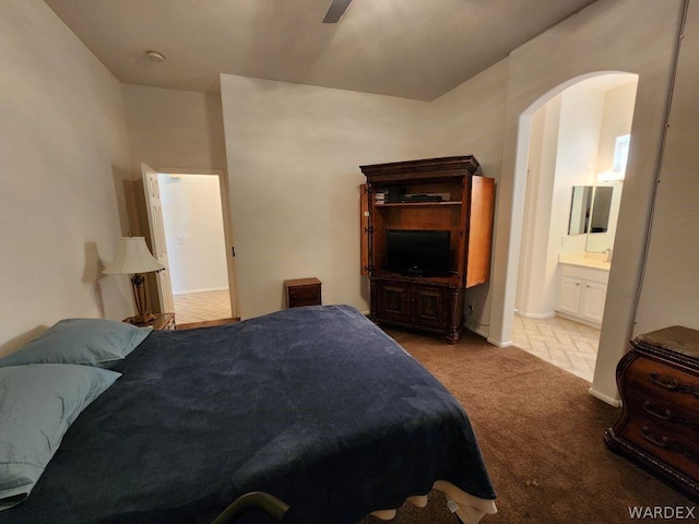 bedroom featuring arched walkways, light colored carpet, and connected bathroom