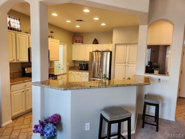 kitchen featuring visible vents, white cabinets, dark stone countertops, freestanding refrigerator, and recessed lighting