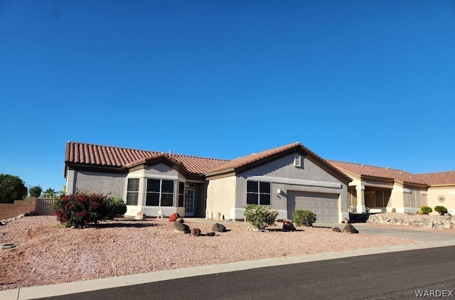 mediterranean / spanish-style house with a garage, driveway, a tiled roof, and stucco siding