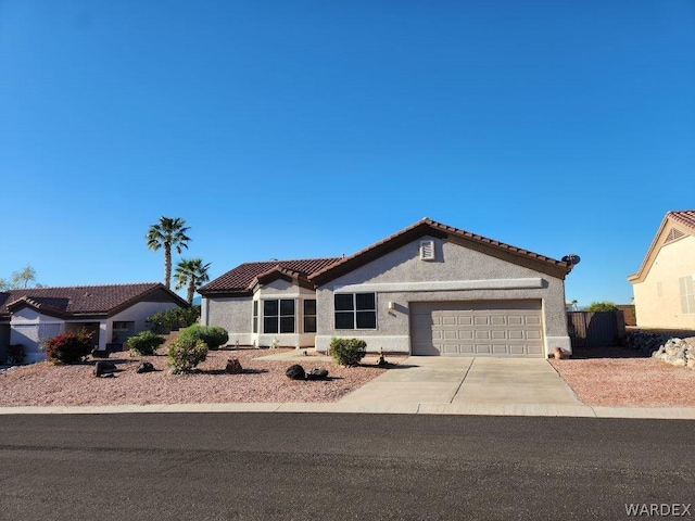 mediterranean / spanish house featuring driveway, a tiled roof, a garage, and stucco siding