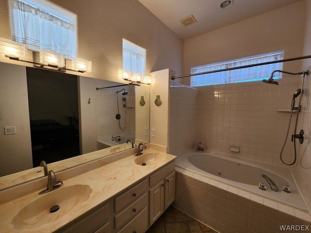 bathroom featuring tiled shower / bath combo, double vanity, visible vents, and a sink