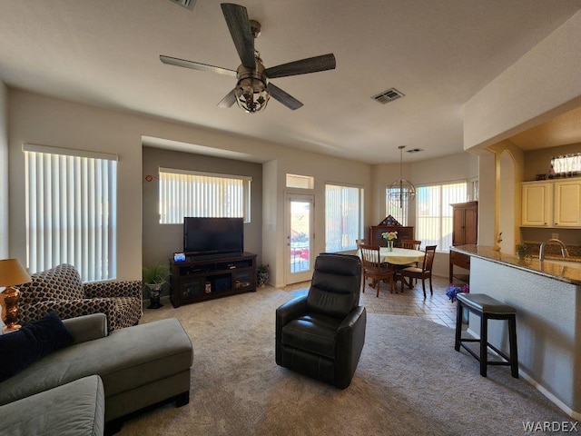 living area featuring light carpet, ceiling fan, and visible vents