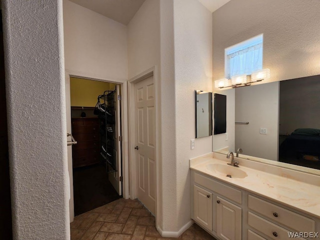 bathroom featuring brick floor, a spacious closet, and vanity