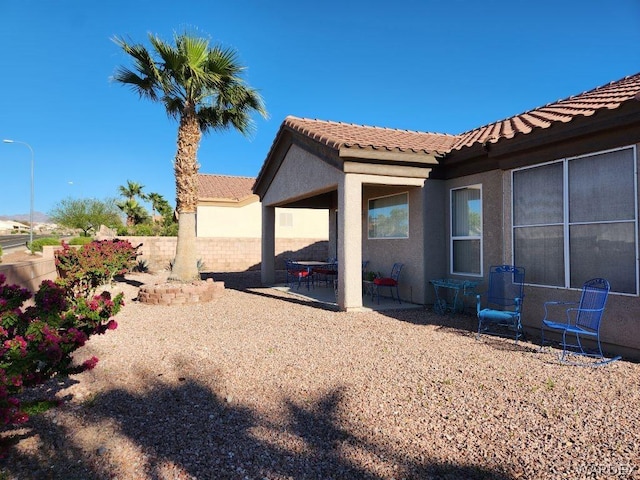 view of property exterior featuring stucco siding, a fenced backyard, a tile roof, and a patio