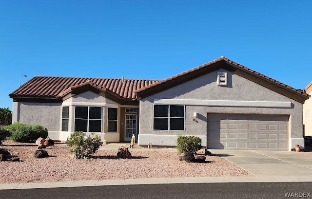 view of front of home with a garage, a tile roof, concrete driveway, and stucco siding