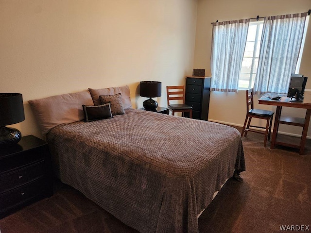 bedroom with dark carpet and baseboards