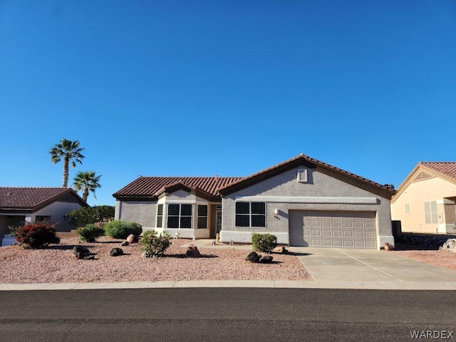 view of front facade with driveway, a tile roof, an attached garage, and stucco siding