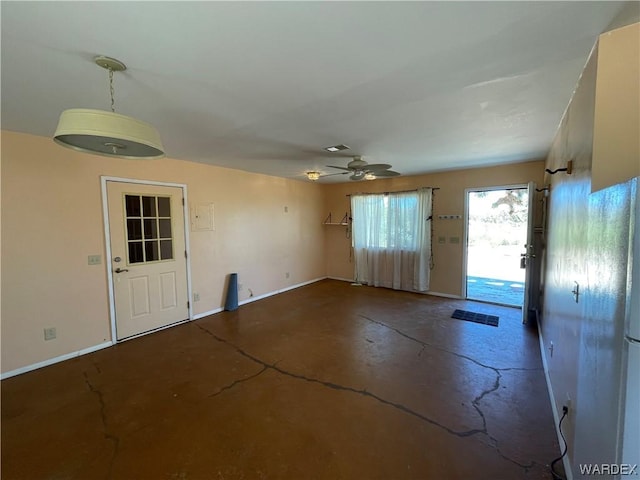 foyer entrance with a ceiling fan, baseboards, and concrete flooring