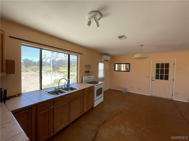 kitchen featuring white electric stove, tile countertops, decorative light fixtures, a sink, and a wall mounted AC