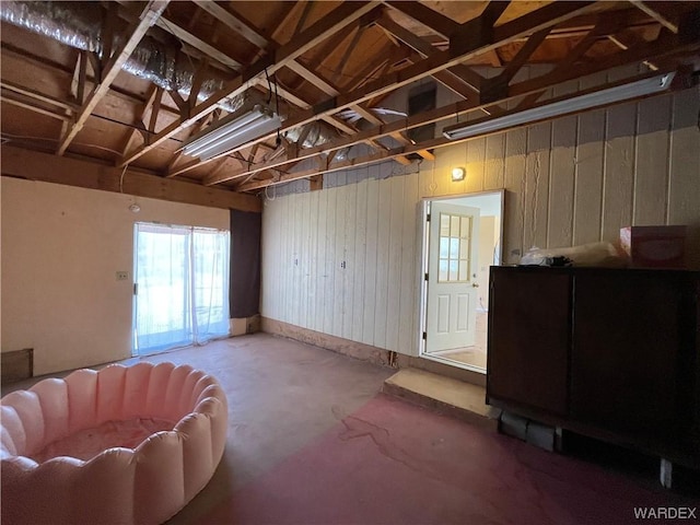 living area with concrete flooring and wooden walls