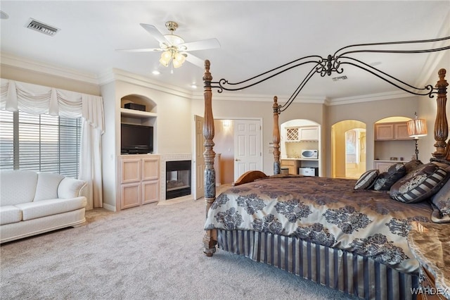 bedroom with visible vents, arched walkways, light colored carpet, ornamental molding, and a multi sided fireplace