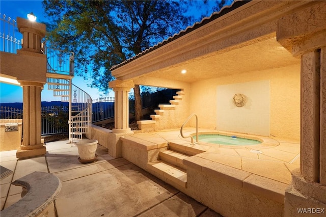 view of patio with fence, stairway, and an in ground hot tub