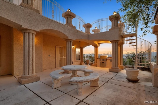 patio terrace at dusk with stairs and area for grilling