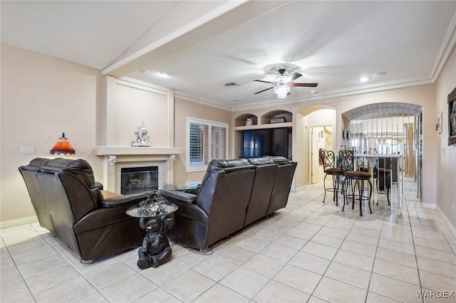 living area featuring light tile patterned floors, a tiled fireplace, visible vents, and a ceiling fan