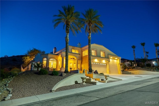 view of front of house featuring a garage, driveway, a chimney, and stucco siding