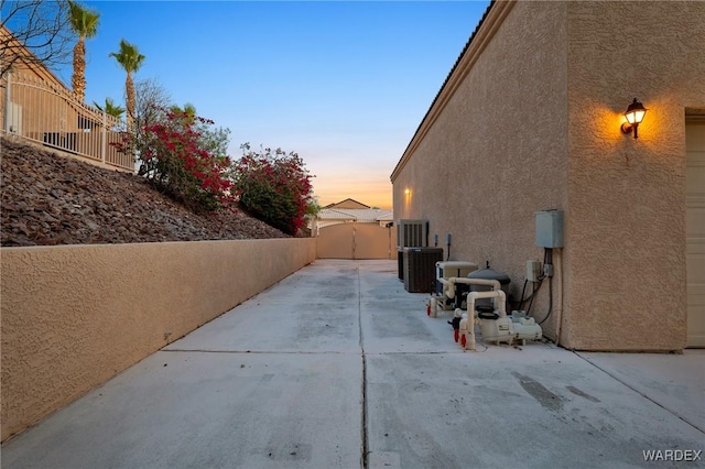 view of side of property featuring cooling unit, a patio area, fence, and stucco siding