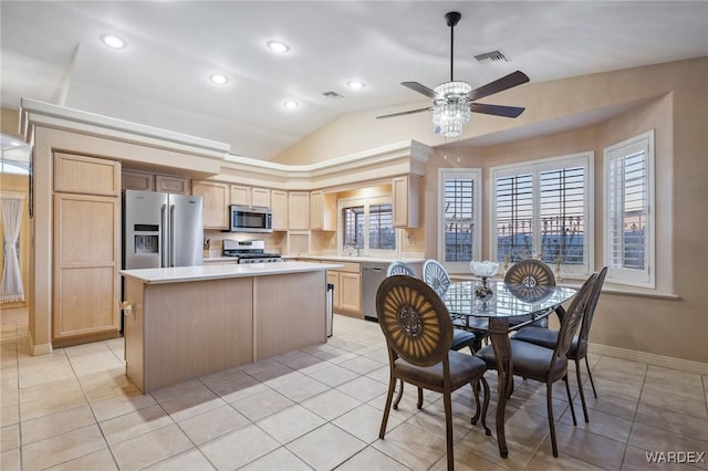 kitchen featuring stainless steel appliances, visible vents, light countertops, a center island, and light brown cabinetry