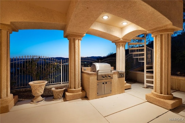 view of patio / terrace with a grill, fence, a mountain view, and an outdoor kitchen