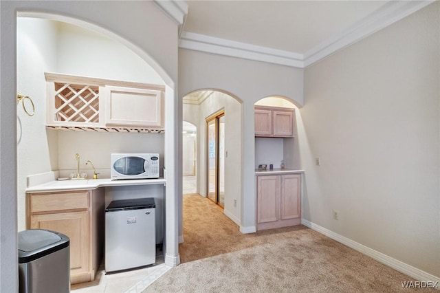 interior space with light carpet, white microwave, freestanding refrigerator, light countertops, and crown molding