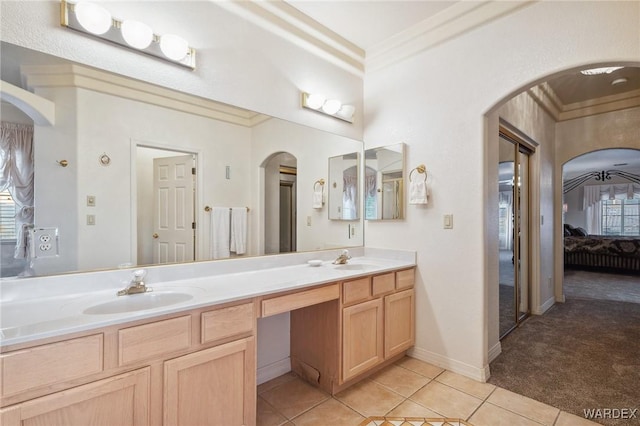 ensuite bathroom featuring double vanity, ensuite bathroom, tile patterned flooring, crown molding, and a sink