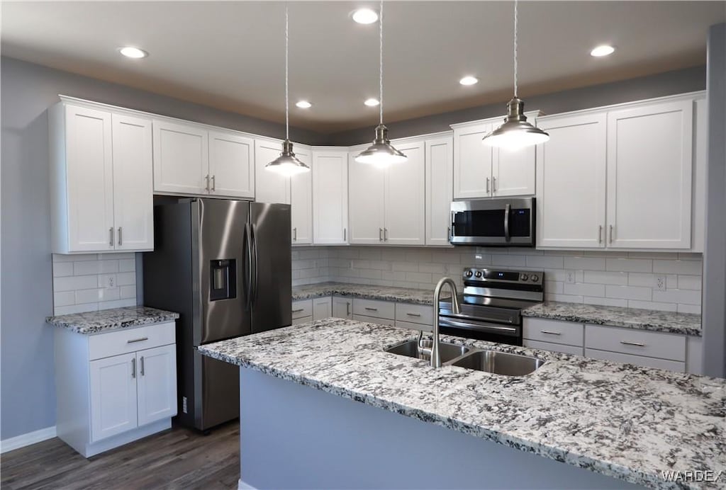 kitchen featuring appliances with stainless steel finishes, a sink, white cabinets, and pendant lighting