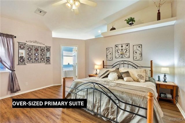 bedroom with visible vents, ensuite bathroom, vaulted ceiling, wood finished floors, and baseboards