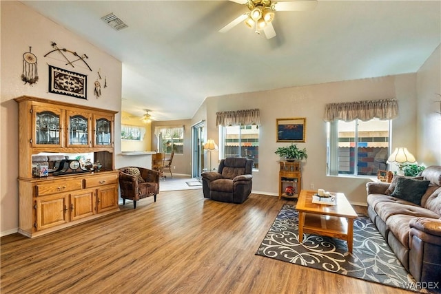 living room with vaulted ceiling, light wood-type flooring, visible vents, and plenty of natural light