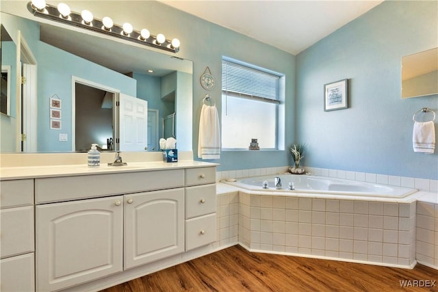 full bathroom featuring a bath, wood finished floors, and vanity