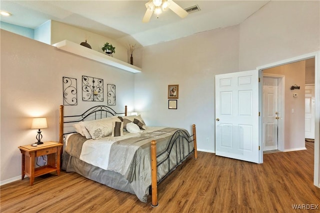 bedroom with high vaulted ceiling, wood finished floors, visible vents, and baseboards