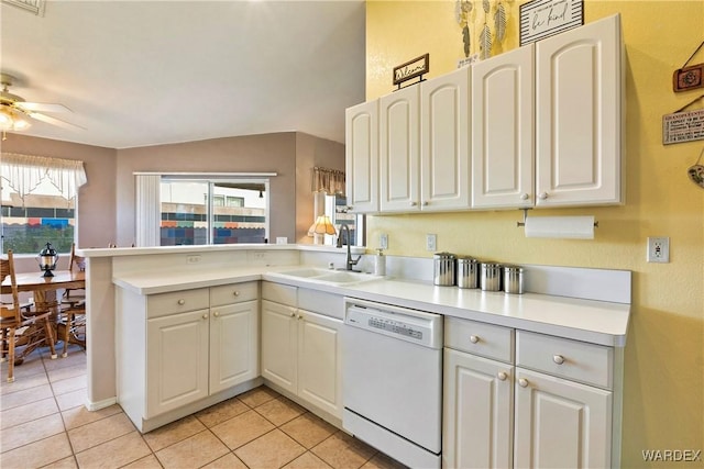 kitchen with light countertops, white cabinets, a sink, dishwasher, and a peninsula