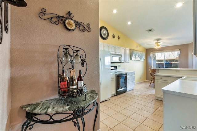 kitchen featuring stainless steel microwave, white cabinets, electric stove, and light countertops