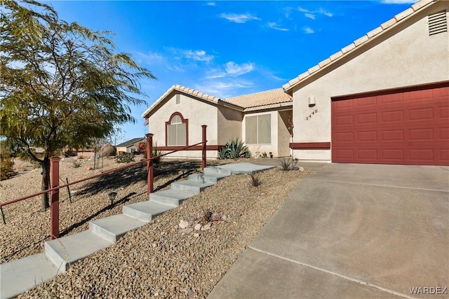 view of front of house with a tiled roof, an attached garage, and stucco siding