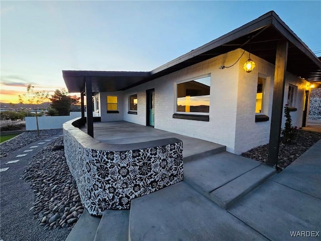 property exterior at dusk featuring a patio and fence