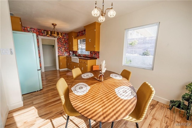 dining room featuring a notable chandelier, light wood-style flooring, and baseboards