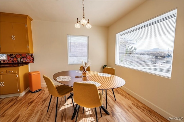 dining area with light wood-type flooring, baseboards, and a chandelier