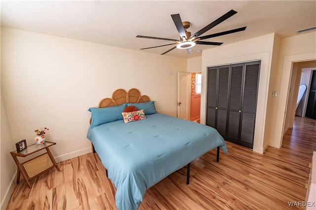 bedroom with light wood-style flooring, a ceiling fan, visible vents, baseboards, and a closet