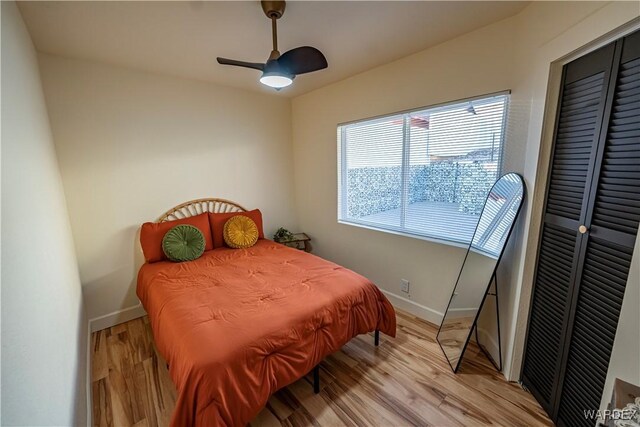 bedroom featuring a ceiling fan, light wood-style flooring, and baseboards