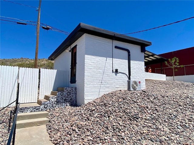 view of home's exterior featuring brick siding, ac unit, and fence