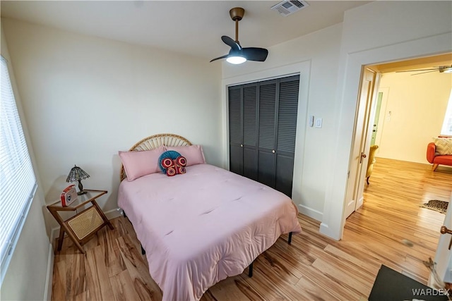 bedroom featuring light wood-style floors, a ceiling fan, visible vents, and a closet