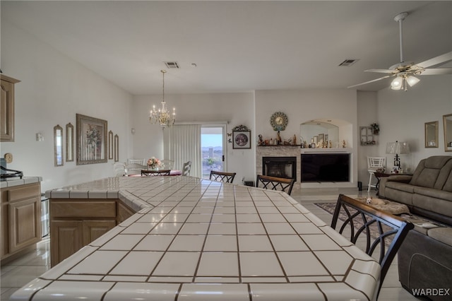 kitchen featuring open floor plan, tile countertops, visible vents, and a fireplace