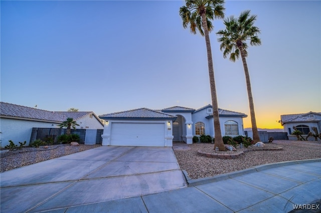 ranch-style home featuring a tiled roof, stucco siding, fence, an attached garage, and driveway