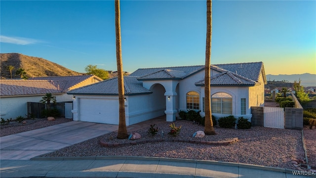 view of front of home with stucco siding, a mountain view, an attached garage, a tile roof, and fence