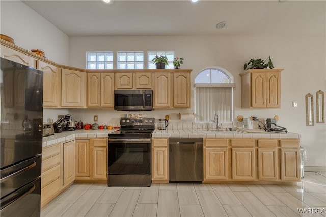 kitchen featuring tile counters, light brown cabinets, and stainless steel appliances