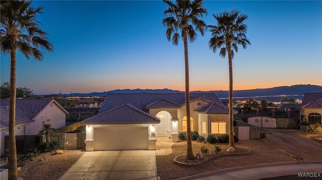 ranch-style home featuring stucco siding, driveway, an attached garage, a tile roof, and a gate