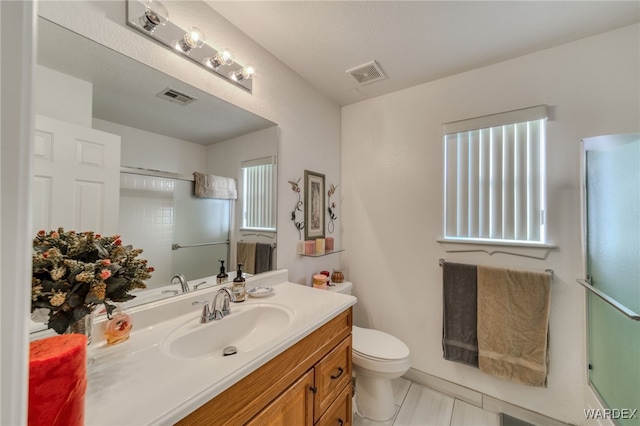 bathroom featuring an enclosed shower, visible vents, toilet, and vanity