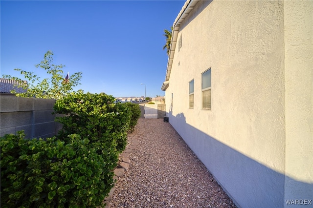 view of side of home with a fenced backyard and stucco siding